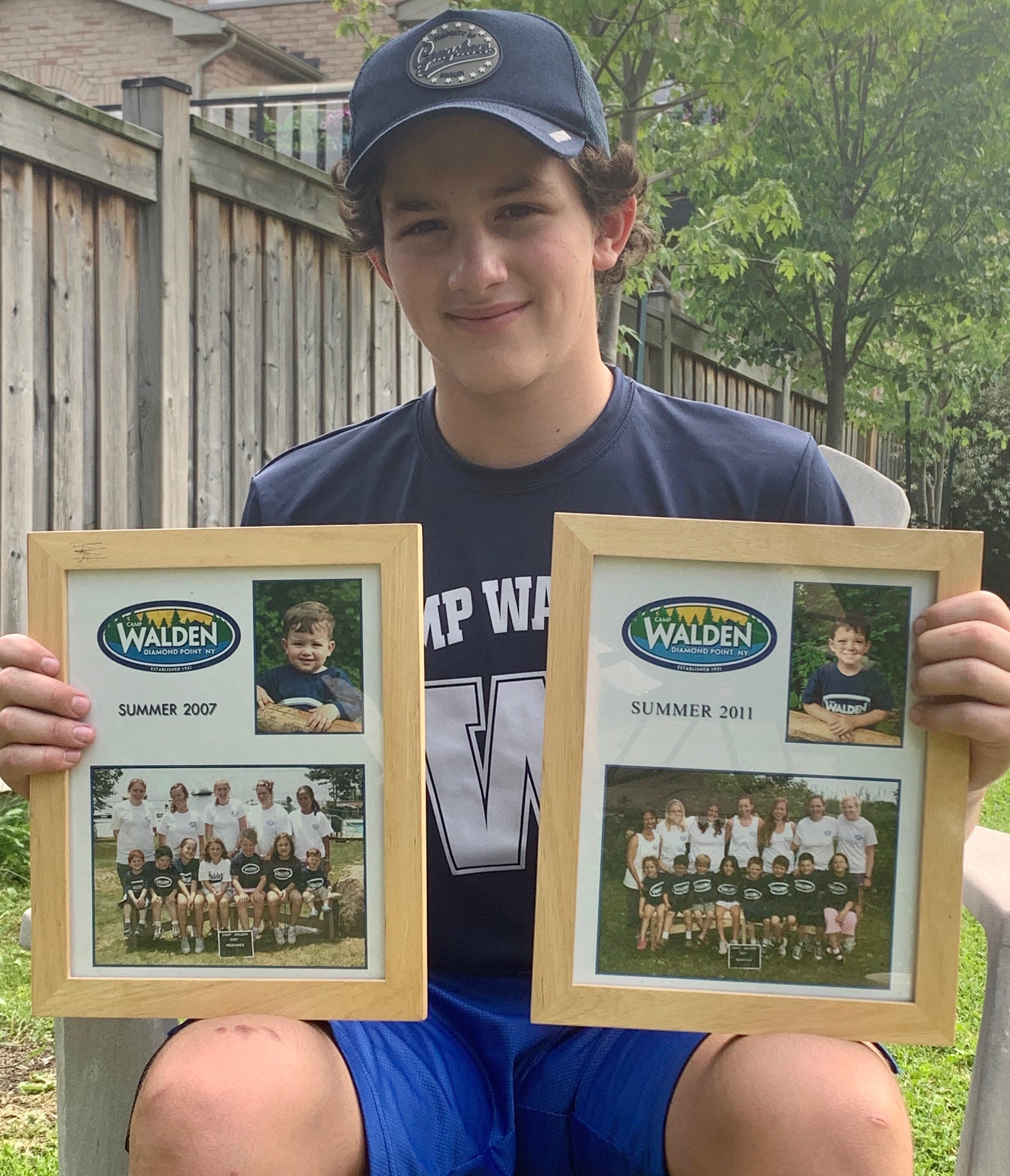 In this June 22, 2020, photo, 14-year-old Rory Sederoff holds framed photos of his previous summers at Camp Walden.